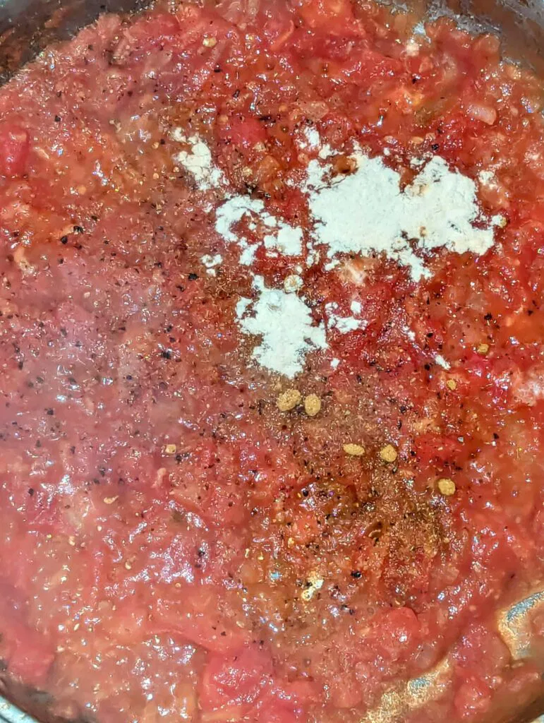 adding spices to shakshuka